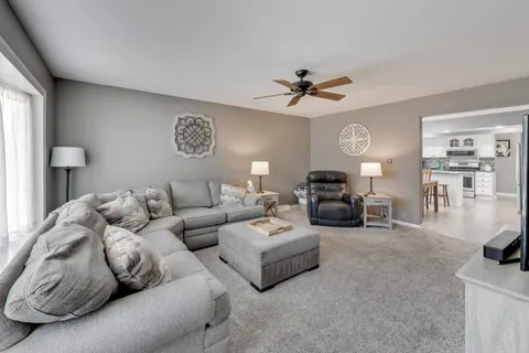a living room with furniture ceiling fan and a window