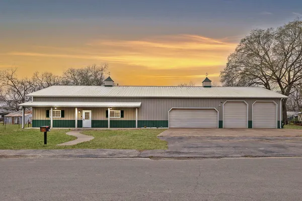 a front view of a house with a garden and trees