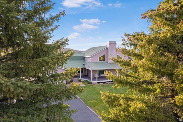 Spacious property featuring a large home with a green metal roof, multiple gables, and a prominent chimney