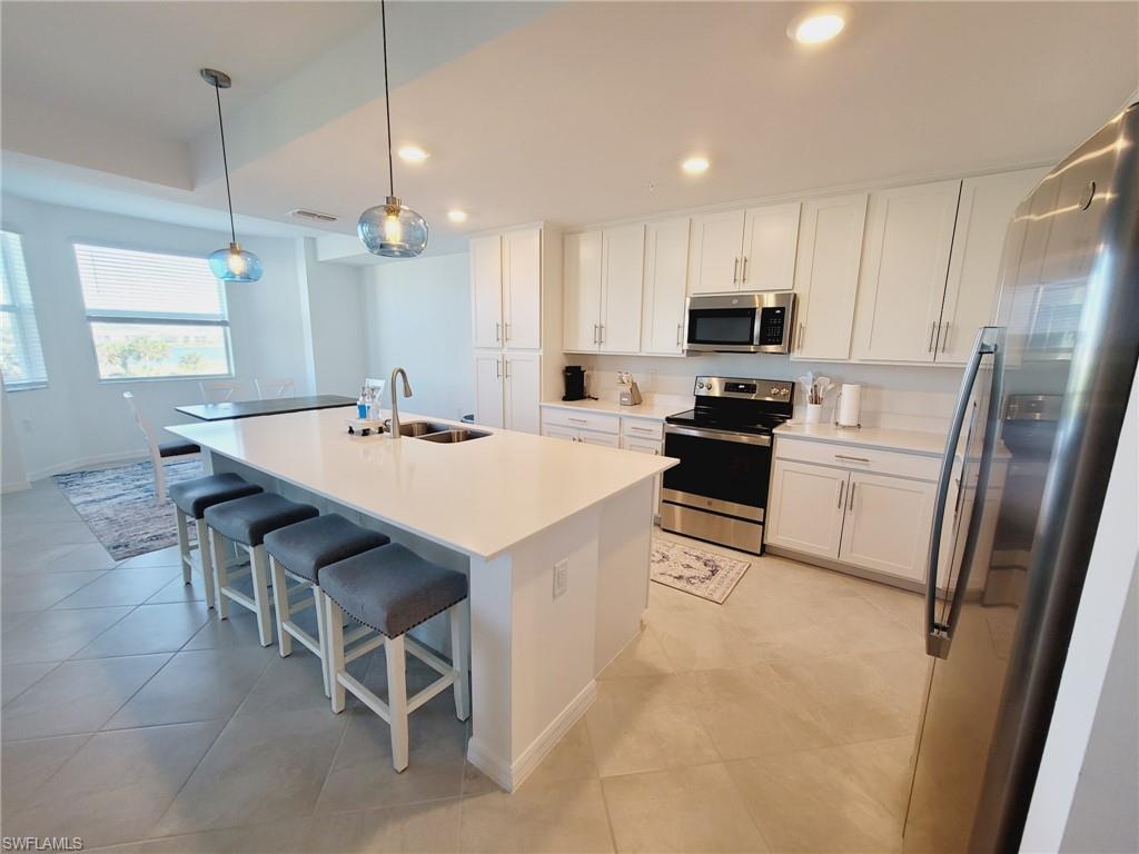 43997 Boardwalk Loop, Unit 1832 Babcock Ranch, FL 33982 - Photo 7 of 22 a kitchen with a sink a stove a refrigerator and white cabinets with wooden floor
