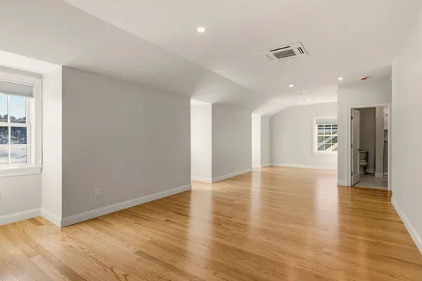 a view of an empty room with wooden floor and a window