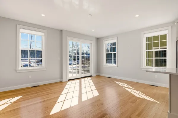a view of an empty room with wooden floor and windows