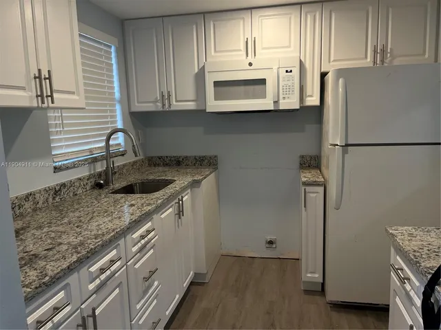 a kitchen with stainless steel appliances granite countertop a refrigerator sink and microwave