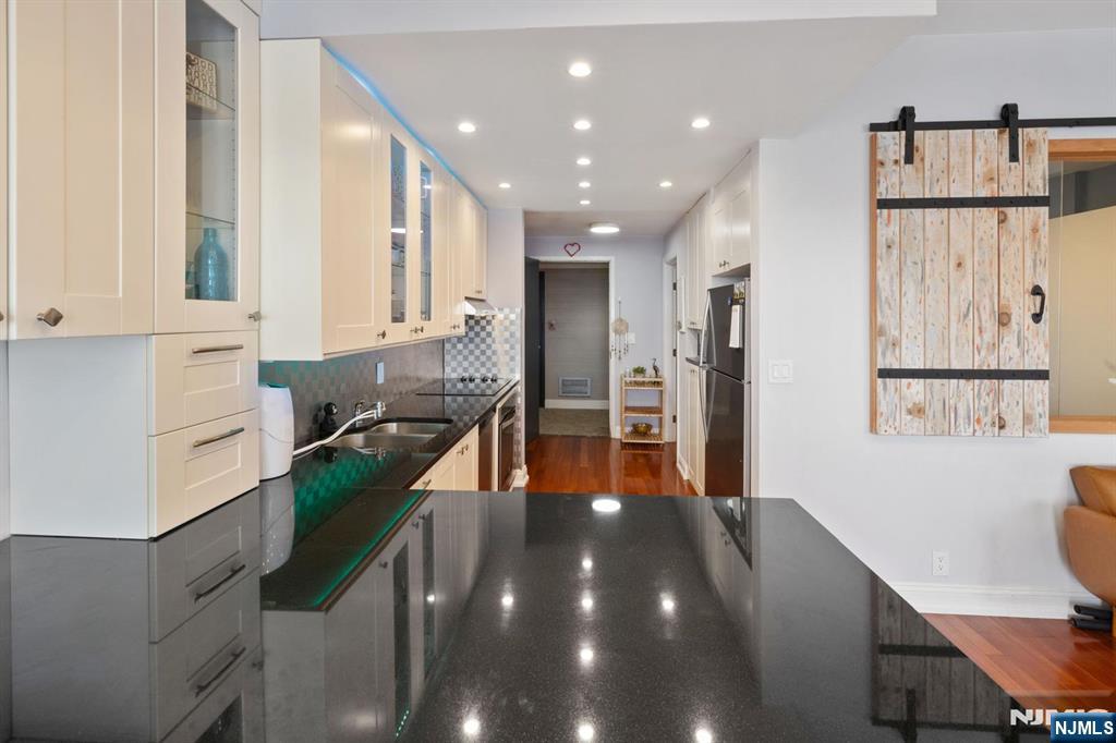 6600 JFK Boulevard East, Unit 23J West New York, NJ 07093 - Photo 9 of 26 a kitchen with stainless steel appliances granite countertop a refrigerator and a stove top oven with wooden floor