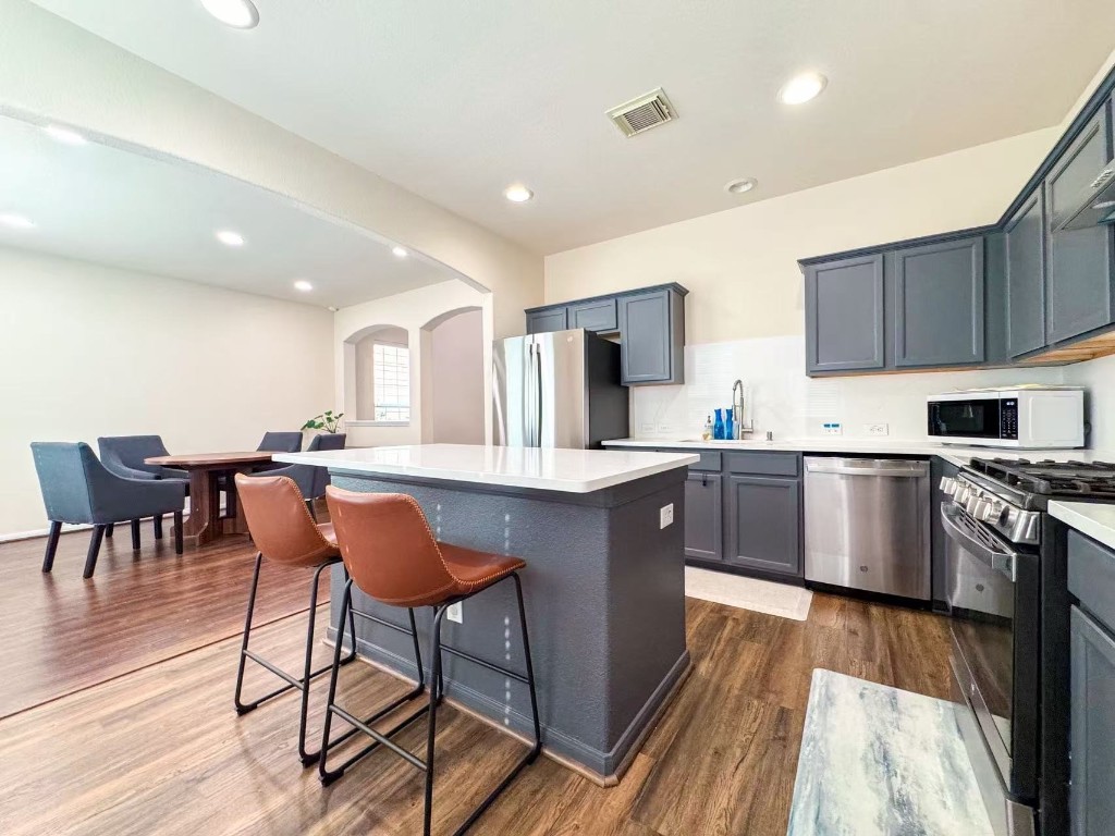 3923 Calgary Circle Missouri City, TX 77459 - Photo 8 of 25 a kitchen with stainless steel appliances granite countertop wooden cabinets a refrigerator a stove a sink dishwasher and a dining table with wooden floor