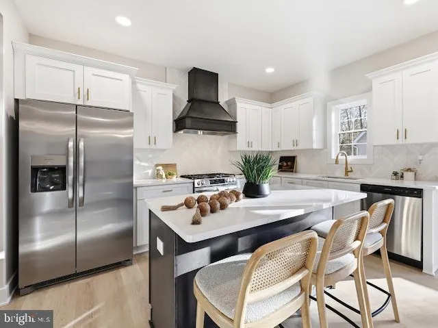 a kitchen with a refrigerator a stove a sink and white cabinets with wooden floor