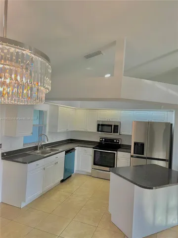 a large kitchen with granite countertop a sink and stainless steel appliances