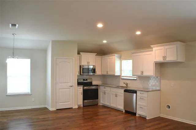 a kitchen with granite countertop white cabinets and white appliances