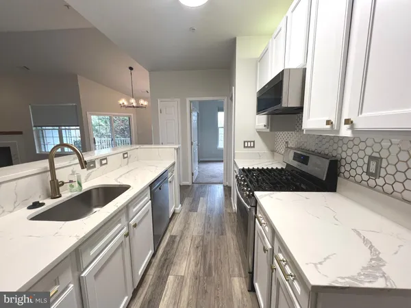a large kitchen with a sink and wooden floor
