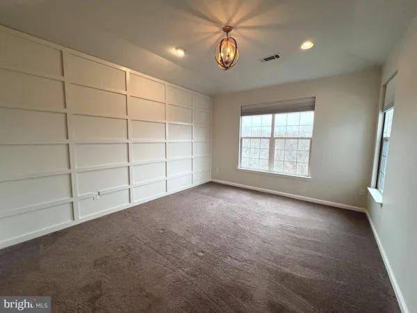 an empty room with windows and chandelier fan