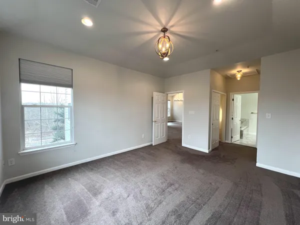 an empty room with chandelier fan and windows