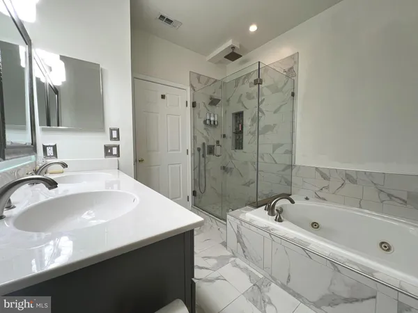 a bathroom with a bathtub a sink a mirror and a shower