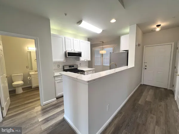 a large white kitchen with a refrigerator a sink dishwasher and a stove with wooden floor