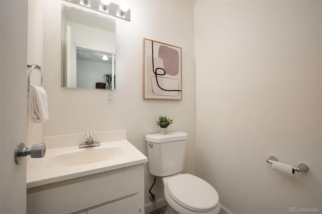 a bathroom with a toilet sink vanity and mirror
