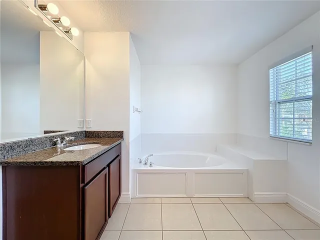 a bathroom with a granite countertop sink and a bathtub