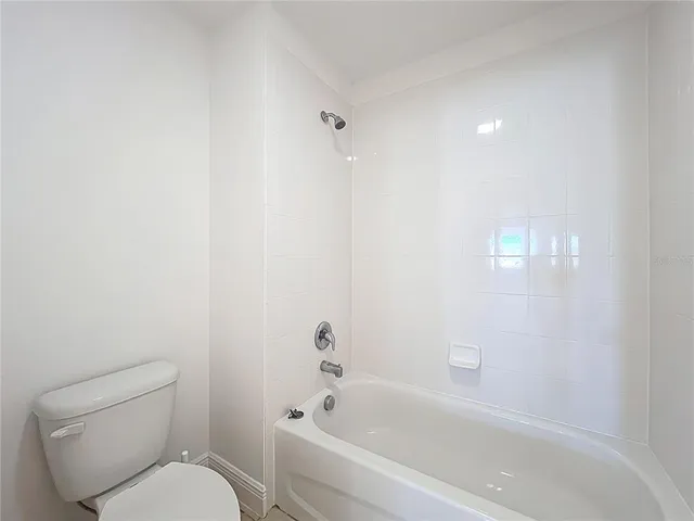 a spacious bathroom with a granite countertop sink a mirror and a bathtub