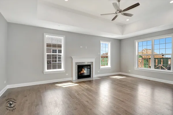 an empty room with windows fireplace and wooden floor