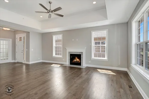 an empty room with wooden floor fireplace and windows