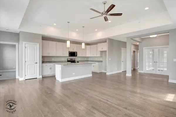 a view of kitchen with stainless steel appliances refrigerator oven stove and white cabinets with wooden floor