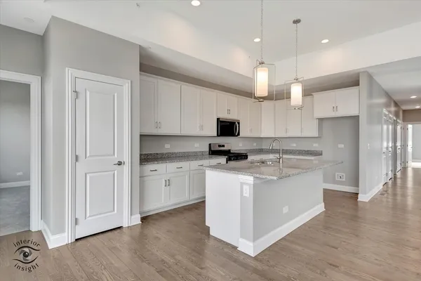 a kitchen with stainless steel appliances granite countertop a refrigerator a stove a sink dishwasher and white cabinets with wooden floor