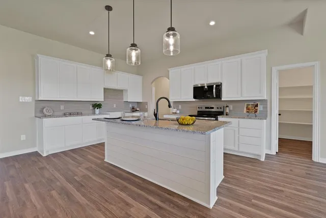a kitchen with granite countertop a stove cabinets and wooden floor