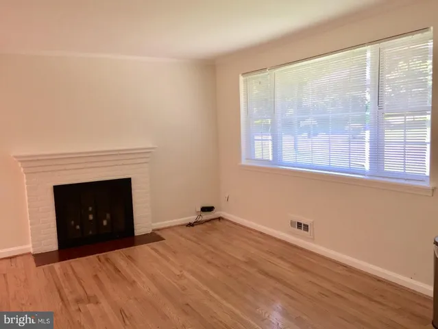 a view of empty room with wooden floor and fireplace