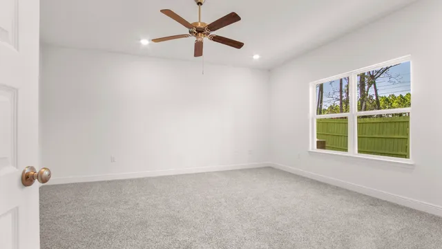 an empty room with a window and a fan