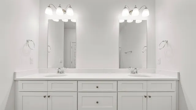 a bathroom with double vanity sinks a vanity a lamp and a mirror