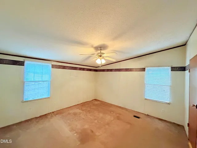 an empty room with windows and fan