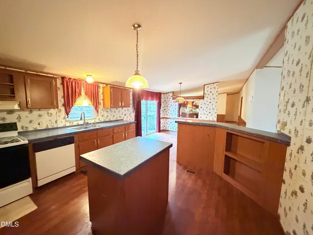 a kitchen with stainless steel appliances granite countertop a refrigerator a sink dishwasher and wooden cabinets with wooden floor