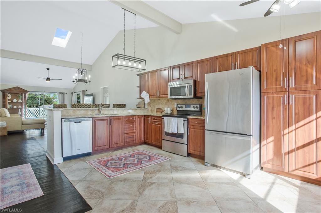 1039 Cardinal Street Naples, FL 34104 - Photo 13 of 29 a kitchen with stainless steel appliances granite countertop a refrigerator a sink a stove a dining table and chairs with wooden floor