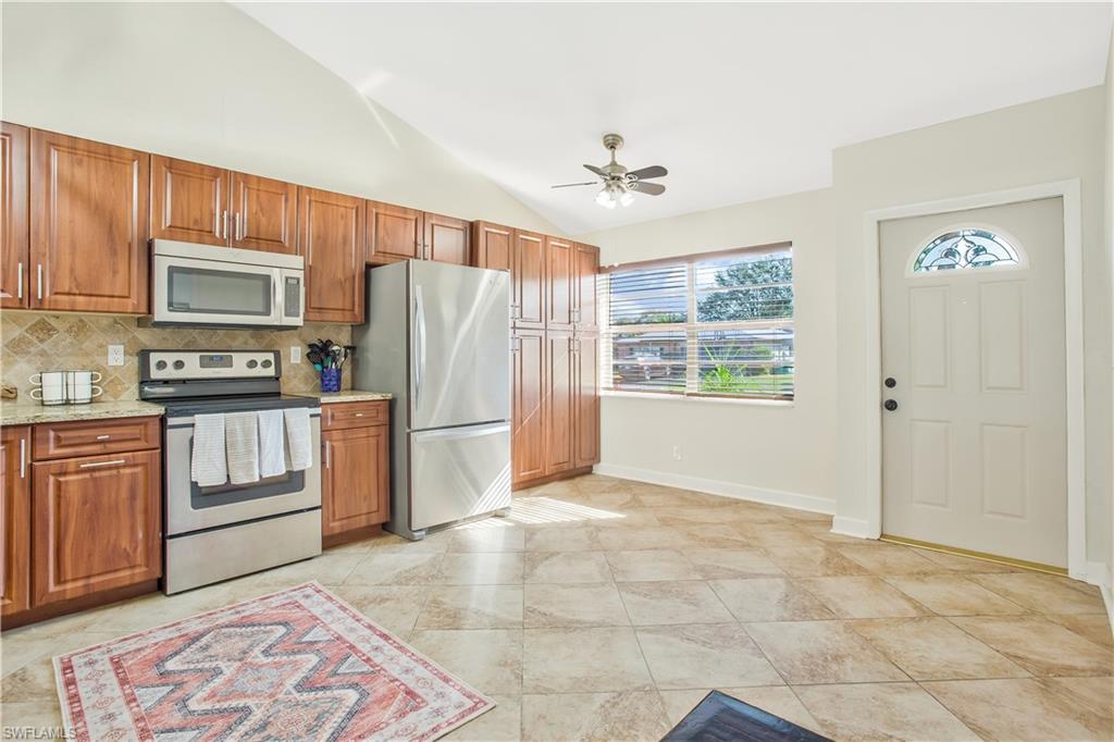 1039 Cardinal Street Naples, FL 34104 - Photo 8 of 29 a kitchen with granite countertop a refrigerator and a stove top oven