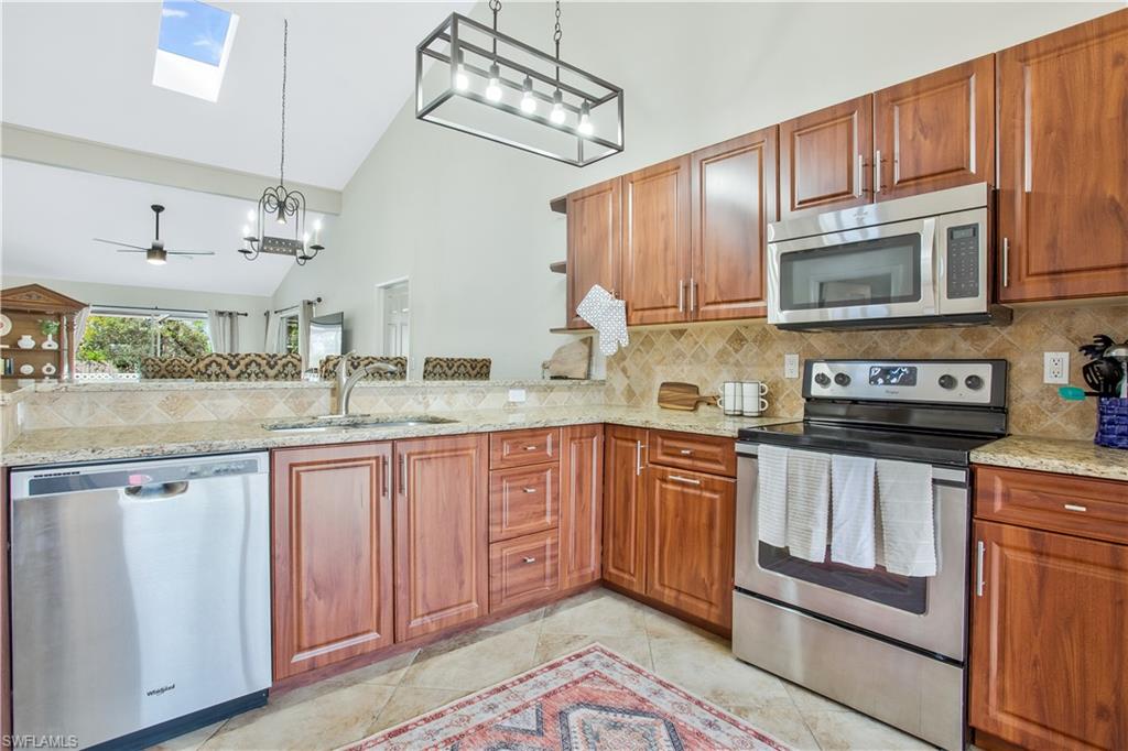 1039 Cardinal Street Naples, FL 34104 - Photo 9 of 29 a kitchen with stainless steel appliances granite countertop a sink and cabinets