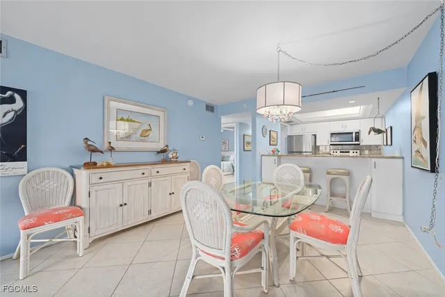 a dining room filled chandelier and kitchen view