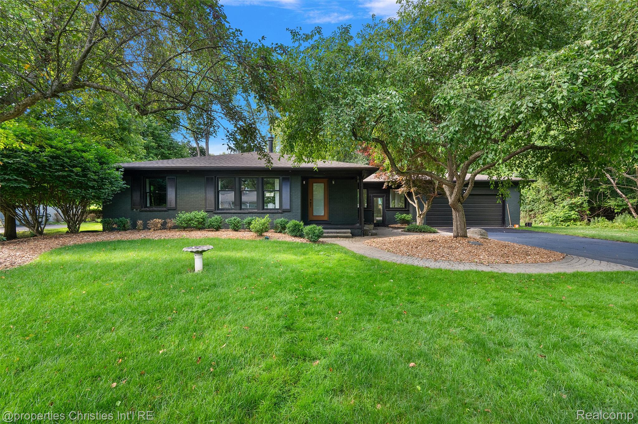 Single-story residence featuring a dark exterior, contrasting trim, and mature landscaping