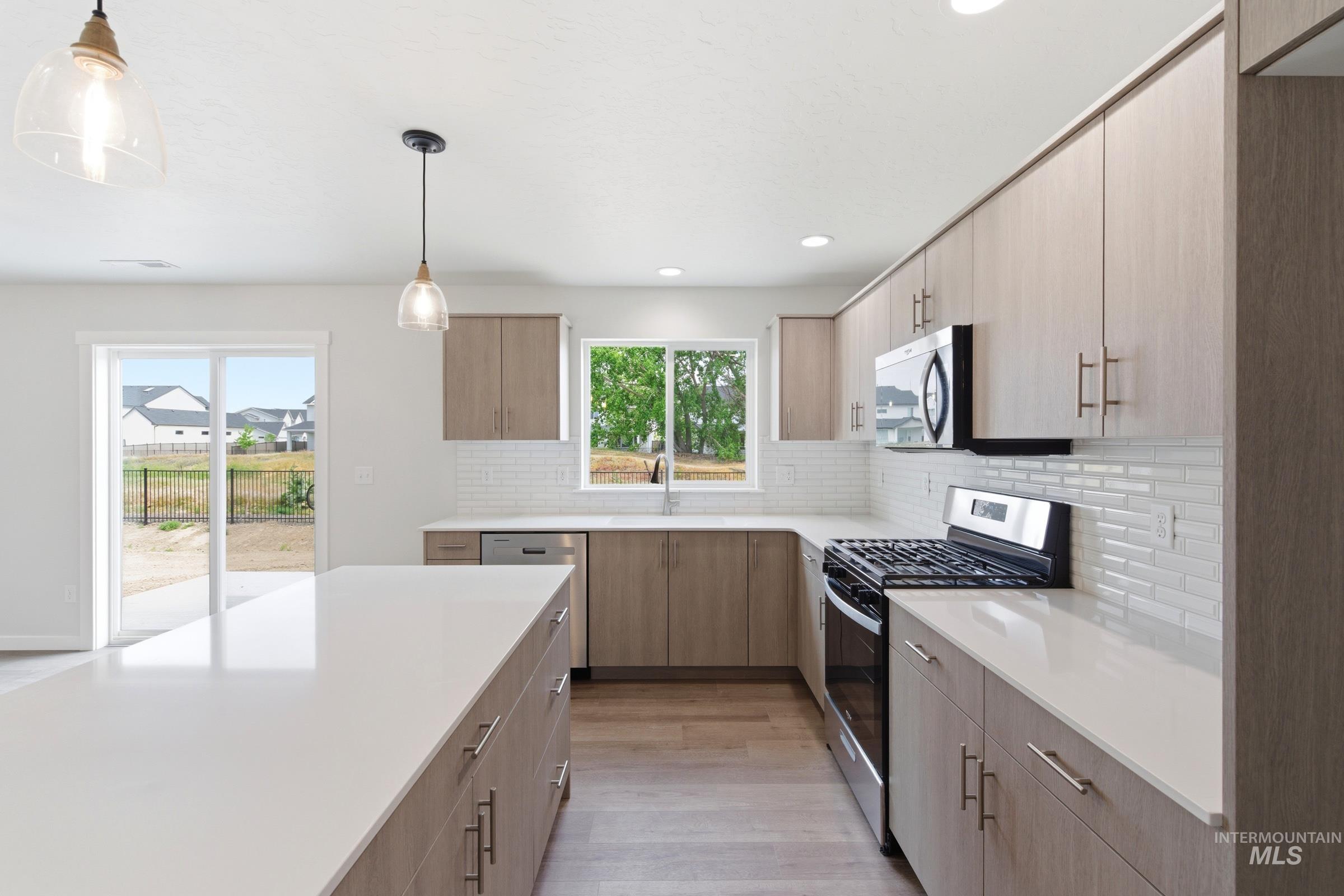 12829 Decatur Street Nampa, ID 83651 - Photo 5 of 33 Modern kitchen featuring light wood-finish cabinetry, white countertops, and a white subway tile backsplash