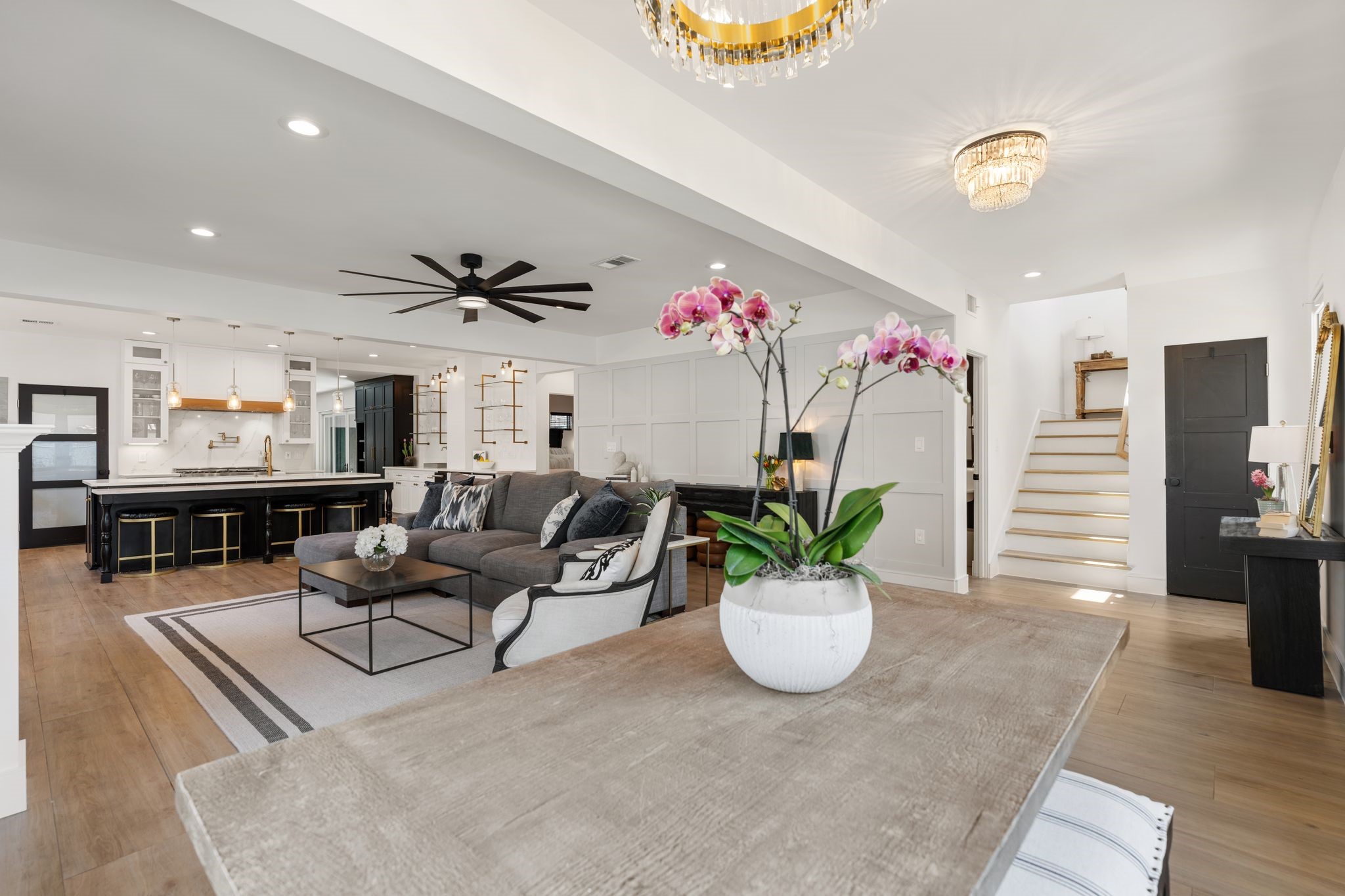 2626 Reagan Street Houston, TX 77009 - Photo 14 of 50 From the dining area, this view highlights the home's open layout connecting the dining room, living room, and kitchen, creating an ideal setup for entertaining and gathering with family and friends. A decorative gold chandelier hangs above the table, adding an elegant touch to the space.