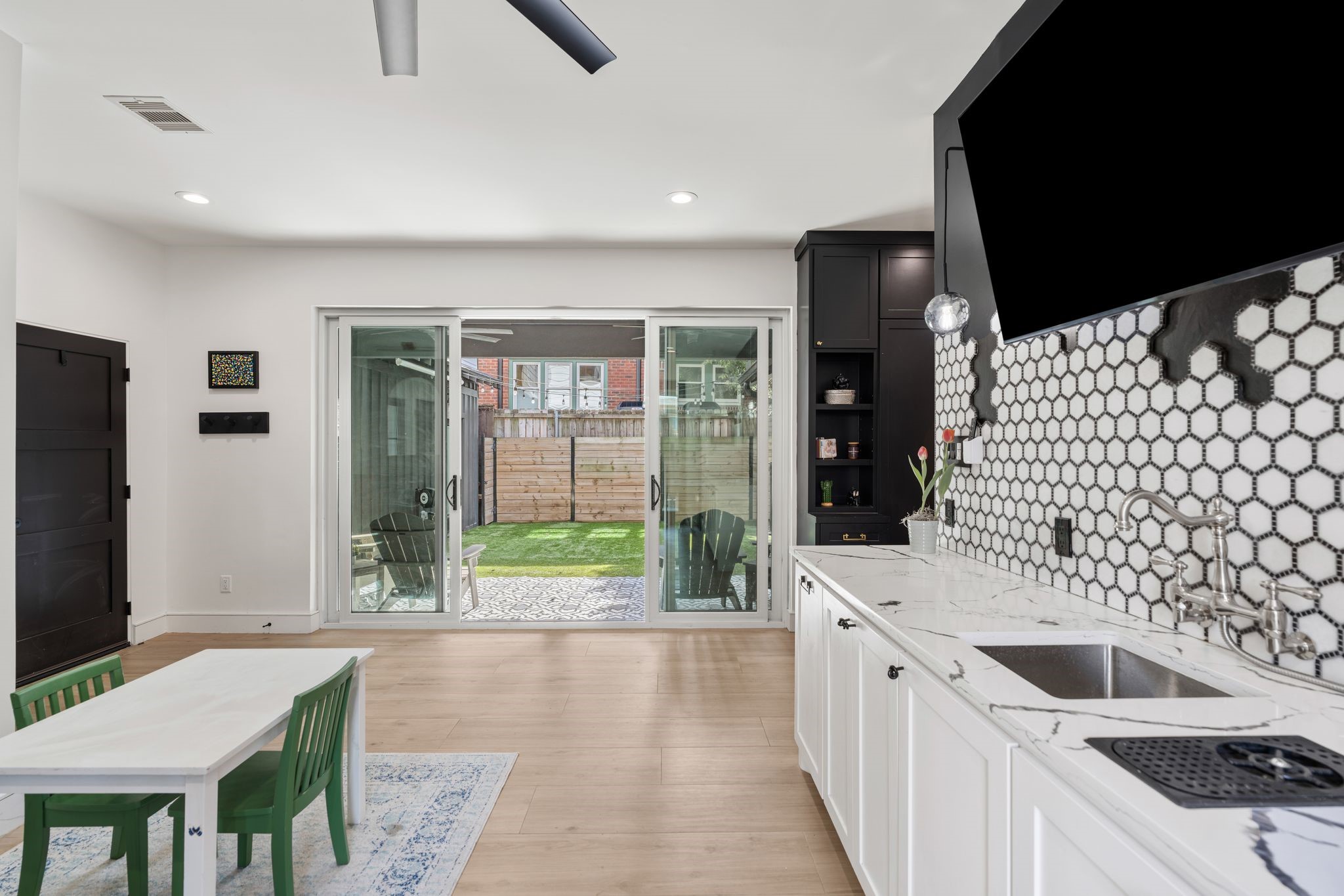 2626 Reagan Street Houston, TX 77009 - Photo 16 of 50 The wet bar features quartz countertops, a decorative tile backsplash, built-in glass rinser, and an oversized wine refrigerator. Two decorative pendant lights hang above the bar while sliding glass doors open to the backyard and provide access to both sides of the yard. A wall of mudroom style cabinetry provides convenient storage around the corner along with a storage closet.
