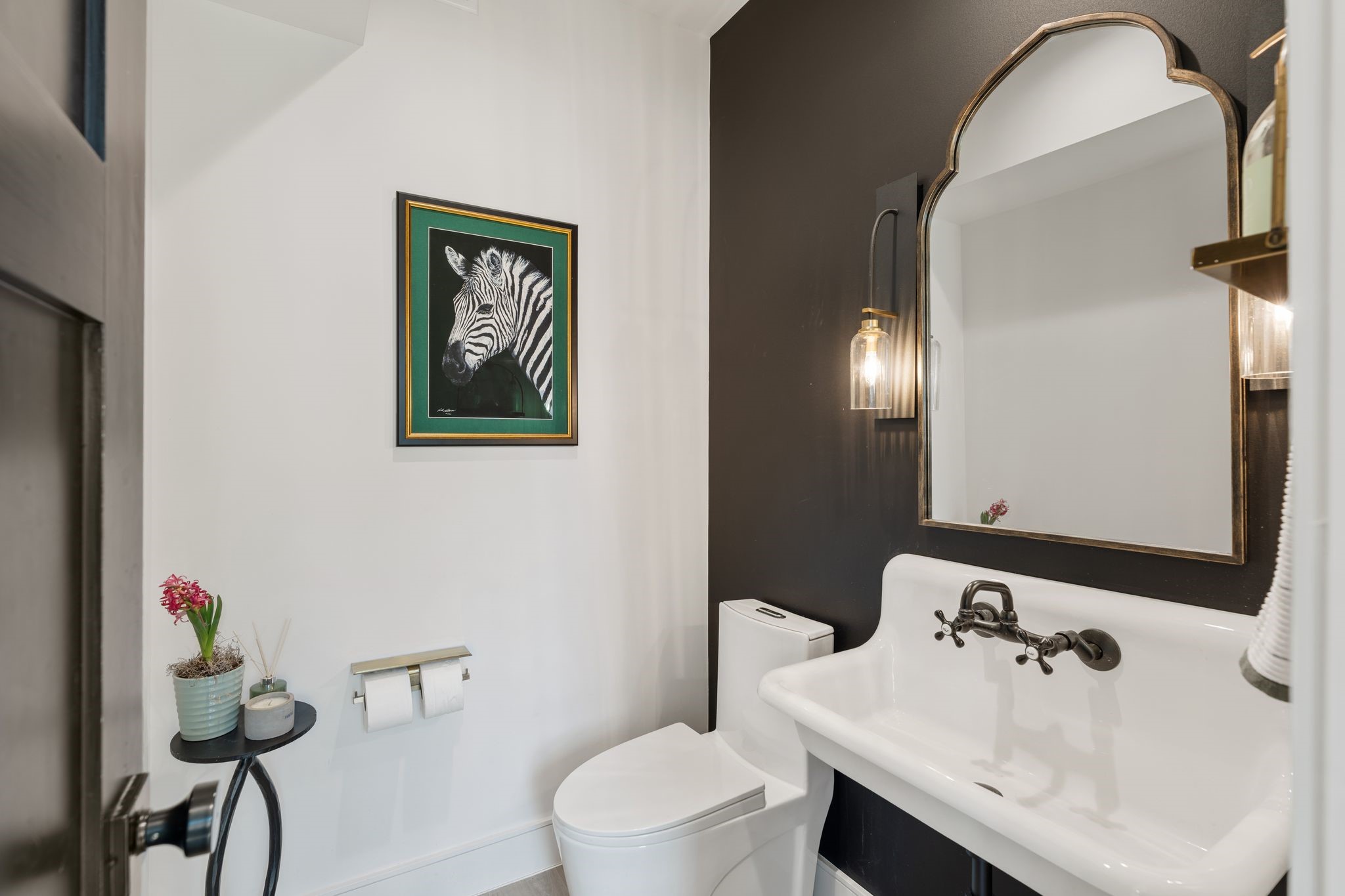2626 Reagan Street Houston, TX 77009 - Photo 17 of 50 The downstairs powder bath features a pedestal sink, decorative mirror, and two sconces complemented by a contrasting accent wall that adds character to the space.
