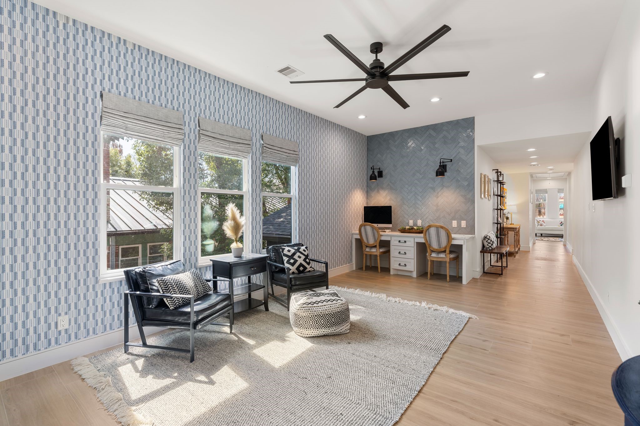 2626 Reagan Street Houston, TX 77009 - Photo 23 of 50 Located at the top of the back stairs, this spacious flex area offers a versatile space that can be used as a playroom, studying area, or additional living space. Built-in desks provide a perfect setup for working from home or for kids doing homework. A striking blue herringbone tile wall is complemented by two decorative light fixtures. Large windows along the wall fill the space of natural light & feature custom blinds, while the pattern wallpaper adds texture & personality to this space.