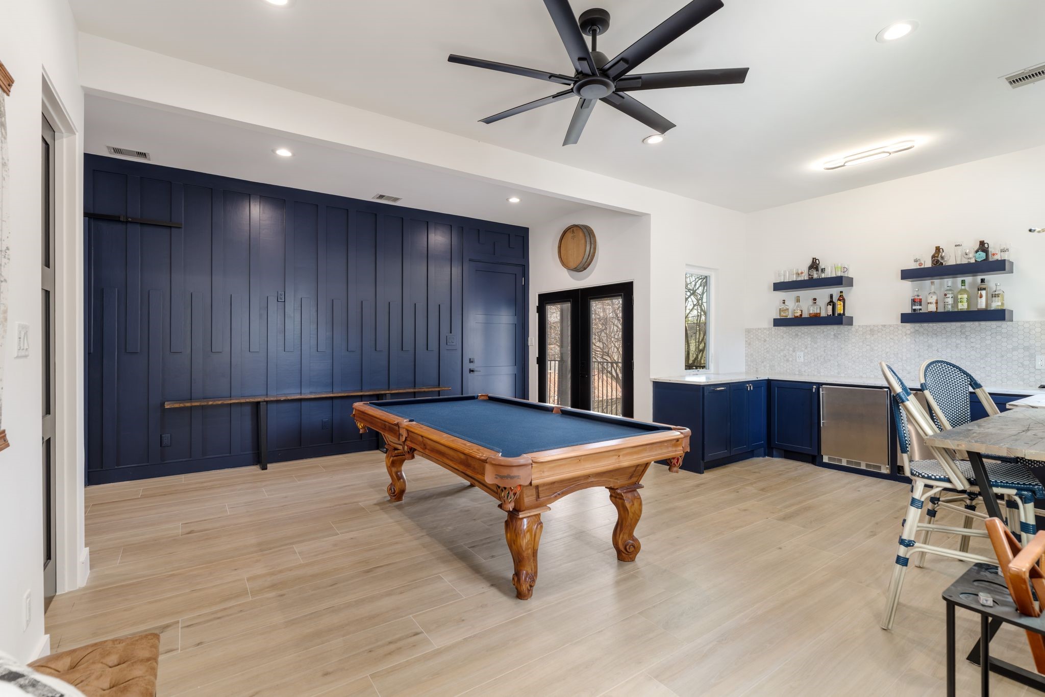 2626 Reagan Street Houston, TX 77009 - Photo 36 of 50 This spacious upstairs game room is designed for entertaining and features an oversized modern ceiling fan and a dramatic floor to ceiling paneled accent wall. A sliding barn door offers flexibility to connect the space to the main home or close it off for privacy allowing it to be part of the guest suite. It also has access to a private stairwell leading to the back guest suite with its own entrance from the driveway.