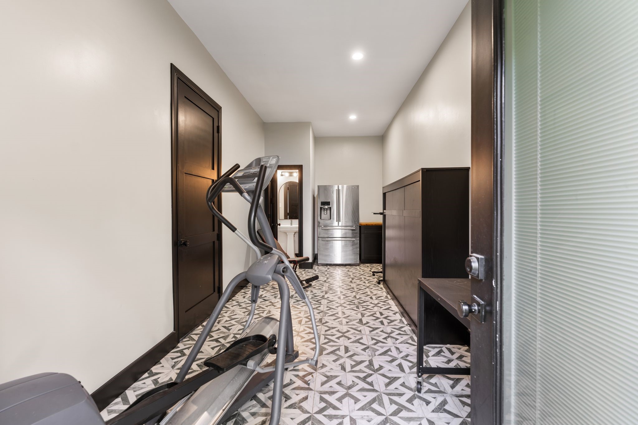 2626 Reagan Street Houston, TX 77009 - Photo 40 of 50 Additional flex space located just off the garage, offering direct access to the backyard and garage ideal for use as a home gym, workshop, or additional living area. The space features decorative pattern tile flooring, a stainless steel refrigerator, washer and dryer hookups for a potential garage apartment, and a conveniently located half bath.