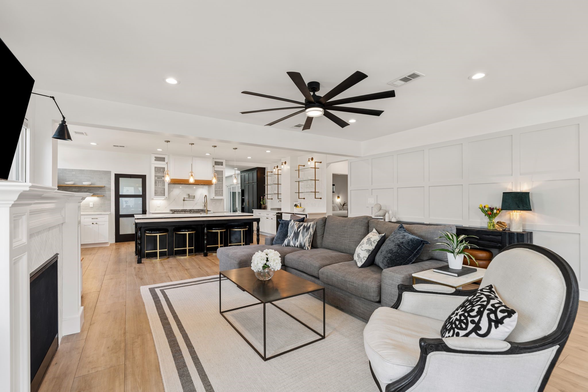2626 Reagan Street Houston, TX 77009 - Photo 5 of 50 The spacious family room features wide plank flooring, a modern ceiling fan, and a paneled accent wall that adds architectural detail. The open concept layout flows seamlessly into the kitchen and dining areas, creating an inviting space designed for both everyday living and entertaining.