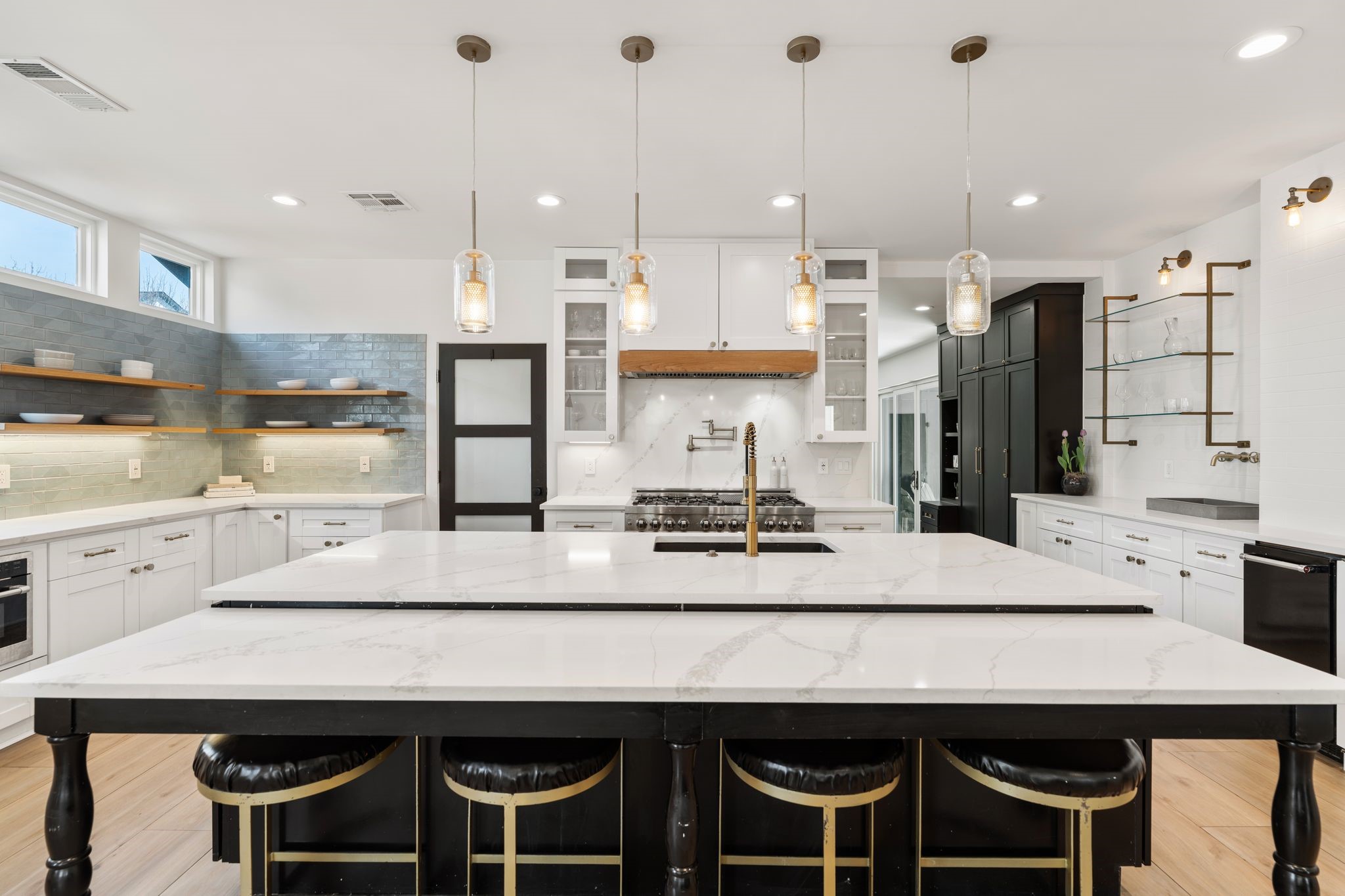 2626 Reagan Street Houston, TX 77009 - Photo 9 of 50 The oversized island serves as a centerpiece of the kitchen, offering generous prep space and seating for guests. gold pendant lighting above the island highlights the quartz countertops and creates a warm, inviting space within the open layout.