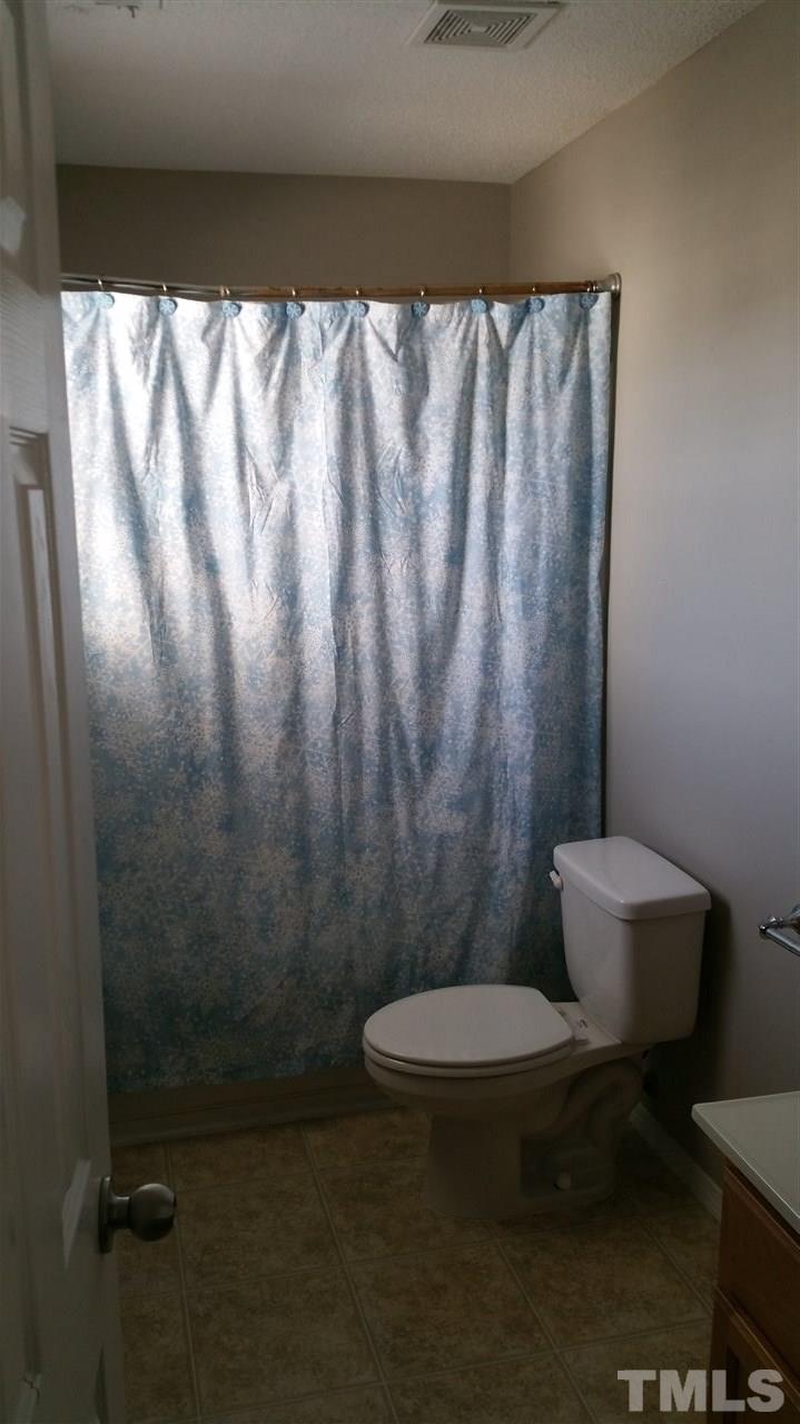 1004 Naylor Road Knightdale, NC 27545 - Photo 18 of 20 a white toilet sitting next to a shower curtain