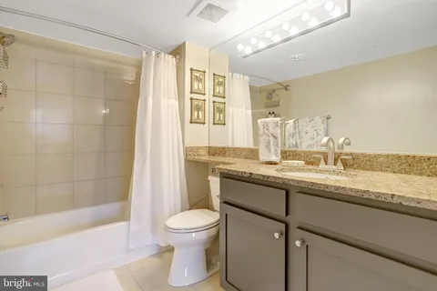 a bathroom with a granite countertop sink a toilet and shower
