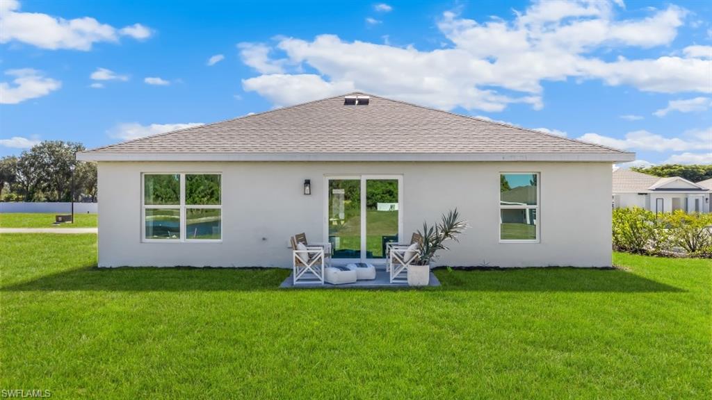 3913 16th Street West Lehigh Acres, FL 33971 - Photo 15 of 15 Model home. Rear view of property with roof with shingles, a yard, stucco siding, and a patio