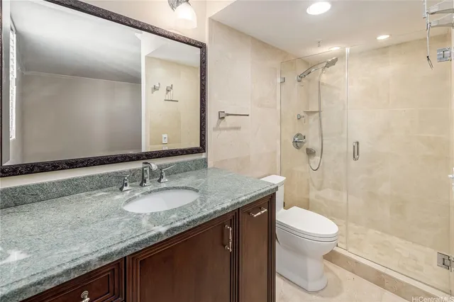 a bathroom with a granite countertop sink a toilet a mirror and shower