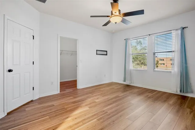 a view of an empty room with window and a chandelier fan