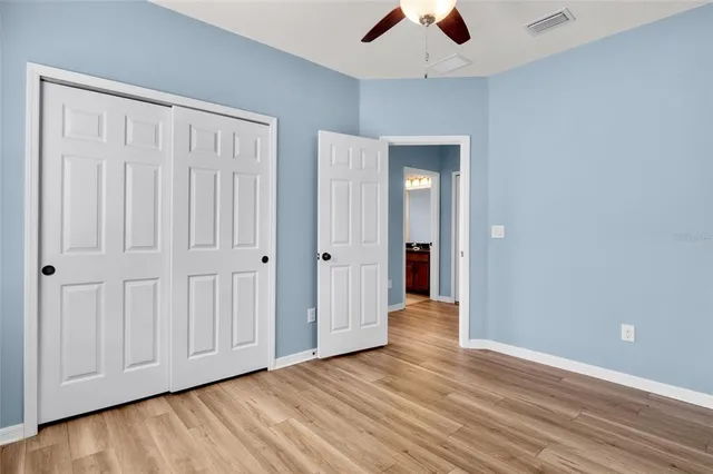 an empty room with wooden floor chandelier fan and windows